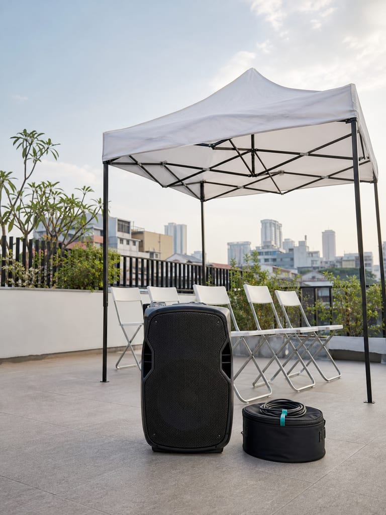 Speaker portabel, tenda acara, kursi lipat, dan tas kabel di teras perkotaan.